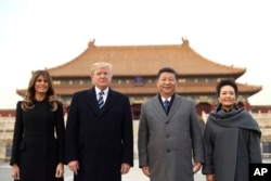 President Donald Trump, second left, first lady Melania Trump, left, Chinese President Xi Jinping, second right, and his wife Peng Liyuan, right, stand together as they tour the Forbidden City, Nov. 8, 2017, in Beijing, China.