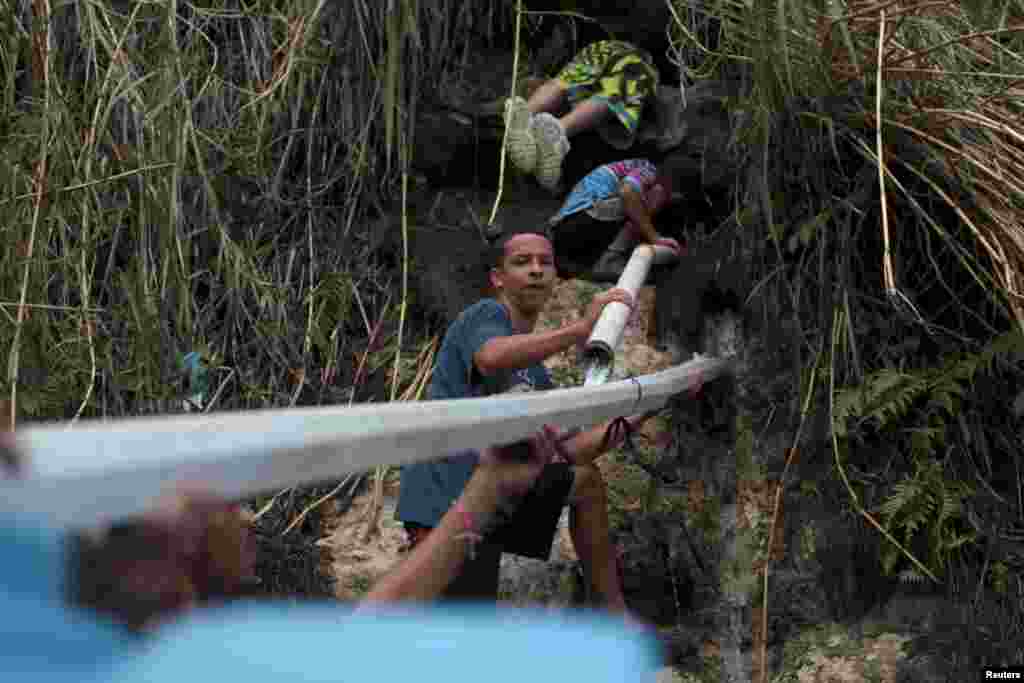 Warga dan anak-anak mencari air minum dari mata air di Corozal, Puerto Rico, yang berusaha memulihkan kehidupan pasca badai Maria.