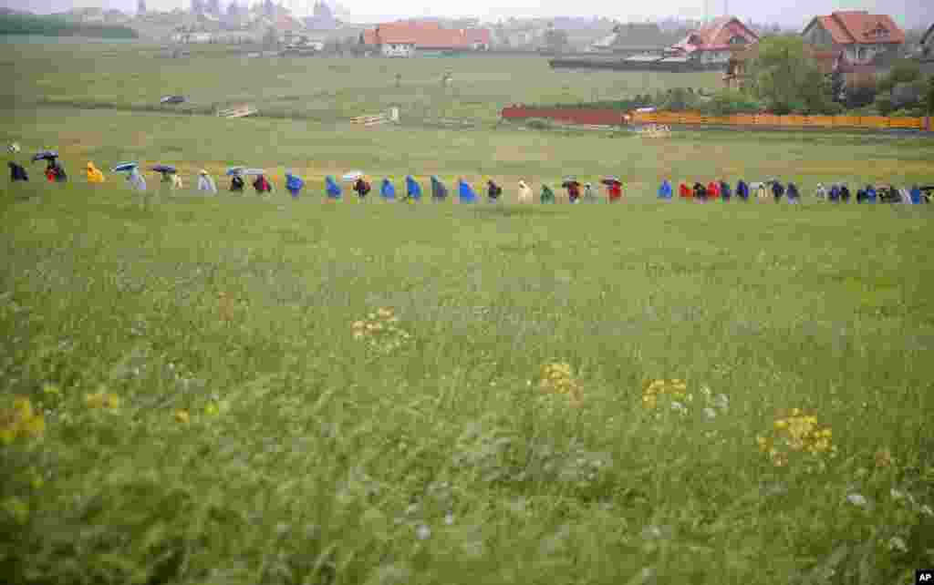 Pilgrims make their way through muddy fields during a heavy rainfall to attend Pope Francis&#39; Mass at the Marian shrine, in Sumuleu Ciuc, Romania, June 1, 2019.