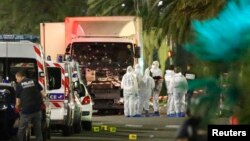 French police force and forensic officers early Friday look at the truck that ran into a crowd celebrating the Bastille Day in Nice, France, July 14, 2016. 