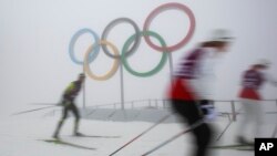 Cross-country skiers train in front of the olympic rings at the Laura biathlon and cross-country ski center, at the 2014 Winter Olympics, Monday, Feb. 17, 2014.