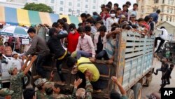 Cambodian migrant workers get off from a Thai truck upon their arrival from Thailand at a Cambodia-Thai international border gate in Poipet, Cambodia, Tuesday, June 17, 2014. The number of Cambodians who have returned home from Thailand this month after a