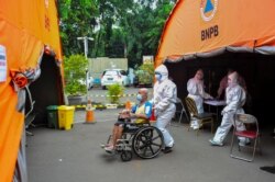 Seorang petugas kesehatan mendorong seorang pasien ke tenda darurat di sebuah rumah sakit di tengah pandemi COVID-19 di Bekasi, di pinggiran Jakarta, 23 Juni 2021. (Foto: Antara/ Fakhri Hermansyah via Reuters)