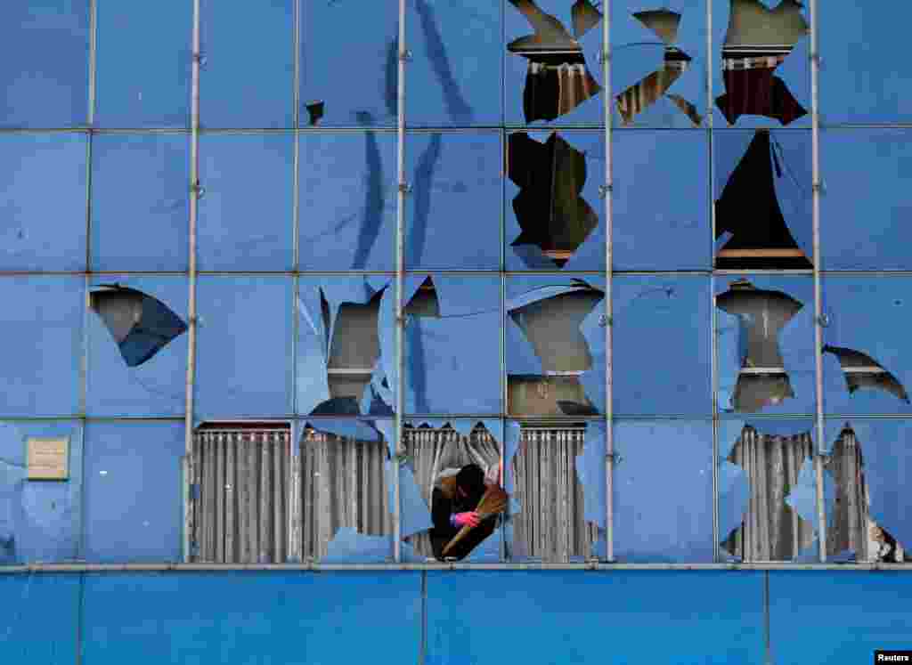 Seorang pria membersihkan pecahan kaca dari sebuah bangunan, pasca serangan bunuh diri di Kabul, Afghanistan.