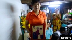 Than Dar, the wife of slain journalist Par Gyi, holds a family photograph showing herself, her husband and daughter posing with Aung San Suu Kyi at their home, in Yangon Oct. 28, 2014.