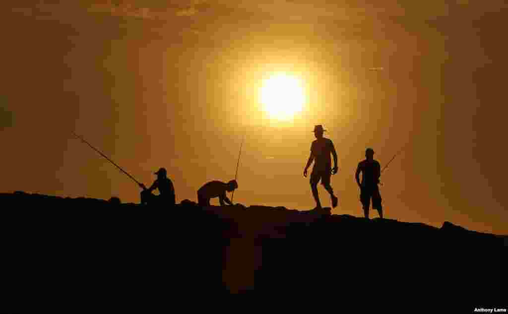 Sri Lankans fishing on the sea front are silhoutted against the setting sun in Colombo.