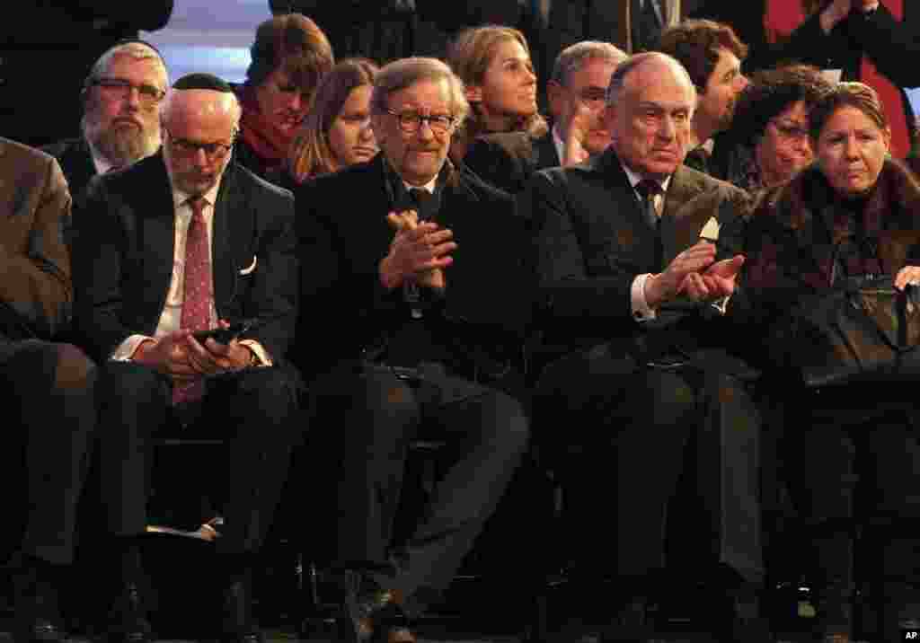 US film director Steven Spielberg, front row, second left, applauds while sitting in a tent raised at the entrance of the Birkenau Nazi death camp in Oswiecim, Poland during the official remembrance ceremony, Jan. 27, 2015.