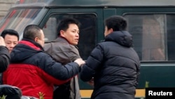 Zhang Xuezhong (C), a lawyer for Chinese dissident Zhao Changqing, argues with plain-clothed policemen as he refuses to show them his identification card in Beijing, Jan. 23, 2014.