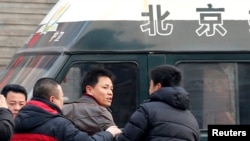 Zhang Xuezhong (C), a lawyer for Chinese dissident Zhao Changqing, argues with plain-clothed policemen as he refuses to show them his identification card when he was stopped and questioned by them on his way to court to attend Zhao's trial in Beijing, Jan. 23, 2014.