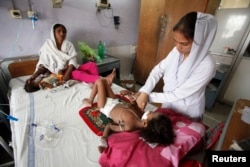 A medic (R) attends to Iqsa, 4, suffering from measles, at the Mayo Hospital in Lahore May 27, 2013. Measles, a highly contagious viral disease, has killed 260 people across Pakistan in 2013 so far, with nearly 11,000 cases reported, according to the Worl