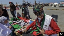 A youth sells hats, flags, and other souvenirs in the colors of the opposition flag to those gathering for Friday prayers in the square next to the courthouse on the corniche in Benghazi, Libya April 15, 2011