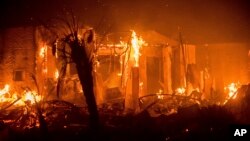 Flames consume a structure as the Lilac fire burns in Bonsai, California, Dec. 8, 2017. 
