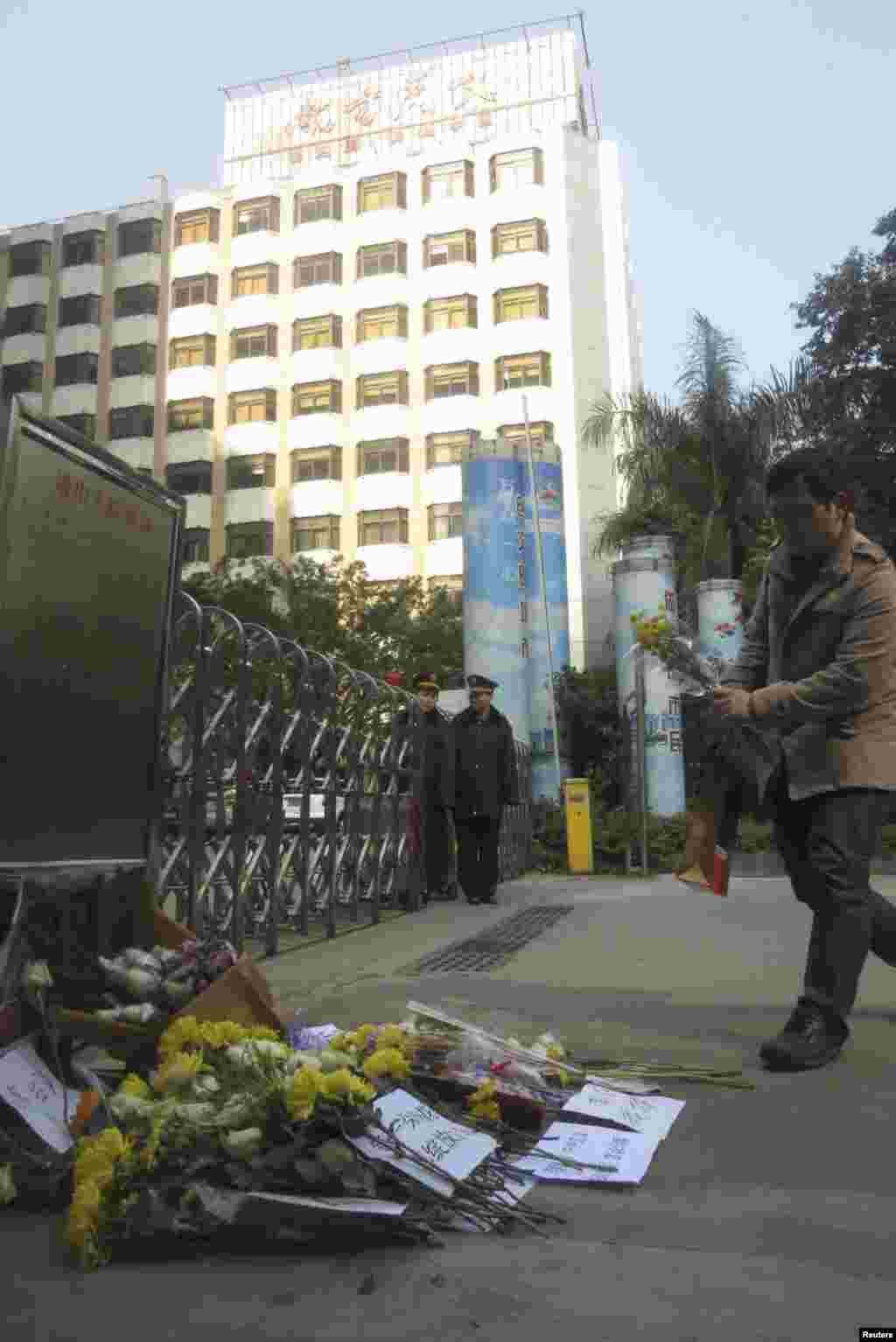 A man lays a bouquet of chrysanthemums in front of the headquarters of Southern Weekly newspaper, January 7, 2013. 