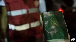 FILE - A rescuer holds a waterlogged Pakistani passport as bodies of migrants who drowned off the coast of Zuwara, Libya, are collected, Aug. 27, 2015.