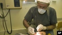 2010 Citizen Diplomat Award recipient Dr. James Rolfe examines the teeth of a young patient at the dental clinic he founded in Afghanistan.