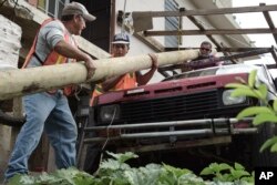 Retired carpenter Felipe Rodriguez, far right, uses his truck to help municipal workers, who are also locals, Eliezer Nazario, left, and Tomas Martinez, move an electric post so they can install it near his home, Jan. 31, 2018, four months after Hurricane Maria hit the El Ortiz sector of Coamo, Puerto Rico.