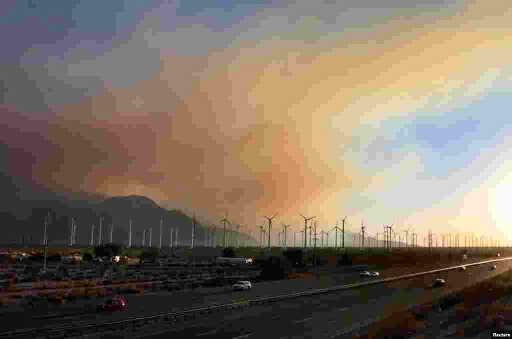 Smoke rises above wind turbines near Interstate 10 in Banning, California August 8, 2013. The wildfire has forced the evacuation of 500 homes in several small communities east of Los Angeles. 