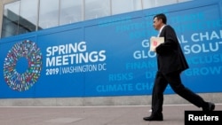 FILE - A man walks outside the International Monetary Fund headquarters building ahead of the IMF/World Bank spring meetings in Washington, Apr. 8, 2019.