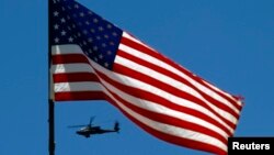 U.S. Army Apache helicopter flies past a flag on Observation Post Mustang in Afghanistan's Kunar Province, June 4, 2012 file photo.