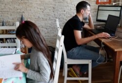 Csaba Posta, IT specialist working from home, studies with his daughter Vilma during the spread of coronavirus disease (COVID-19) in Budapest, Hungary March 19, 2020. REUTERS/Bernadett Szabo