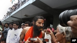 An old Indian woman offers food to yoga guru Baba Ramdev to break his fast in New Delhi, India, Aug. 14, 2012. 