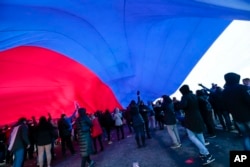 People hold a huge Russian flag during a rally to celebrate the second anniversary of Russia's annexation of Crimea just off Red Square in Moscow, Russia, March 18, 2016. Russia annexed Crimea in 2014 after a hastily organized referendum.