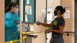 FILE - A patient shows her COVID-19 vaccination card at the Clínica Monseñor Oscar A. Romero in the Pico-Union district of Los Angeles, July 26, 2021.