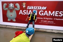 Para pekerja konstruksi membuat jalur pejalan kaki di di depan spandung Asian Games ke-18 di Jakarta, 13 Juli 2018. (Foto: Reuters)