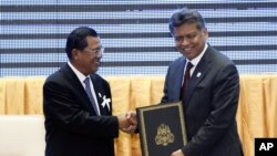 Cambodia's PM Hun Sen, left, with ASEAN Secretary-General Surin Pitsuwan after the ceremony for the adoption of the ASEAN Human Rights Declaration, during the ASEAN Summit in Phnom Penh, November 18, 2012. 