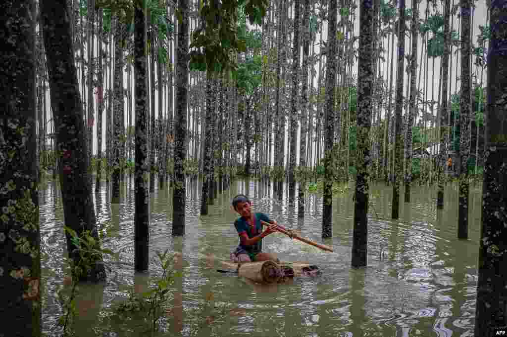 A child wades through a flooded area using a makeshift raft at Maulovir Para, Cox&#39;s Bazar, after monsoon floods and landslides cut off more than 300,000 people in villages across southeast Bangladesh and killed at least 20 people.