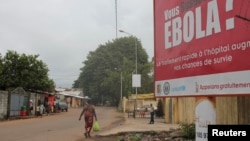 FILE - A billboard with an Ebola message looms over a street in Conakry, Guinea, Oct. 26, 2014.