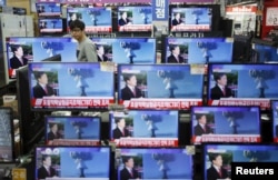 FILE- A sales assistant in Seoul, South Korea, watches TV sets broadcasting a news report on North Korea's nuclear test, Jan. 6, 2016.