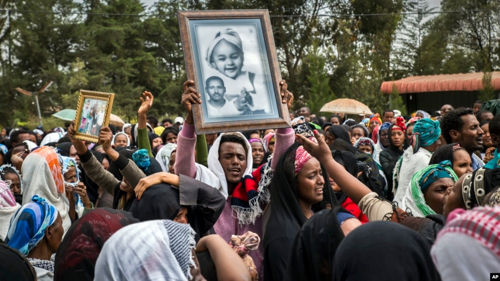 FILE - Relatives mourn as they lift portraits of family members they lost in the collapse of a mountain of trash at a garbage dump, during a funeral service held at Gebrekristos church in Addis Ababa, Ethiopia, March 13, 2017.