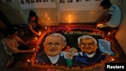 Students place candles around a painting featuring India's former prime minister Atal Bihari Vajpayee to pay him homage in Mumbai, India, Aug. 16, 2018. 
