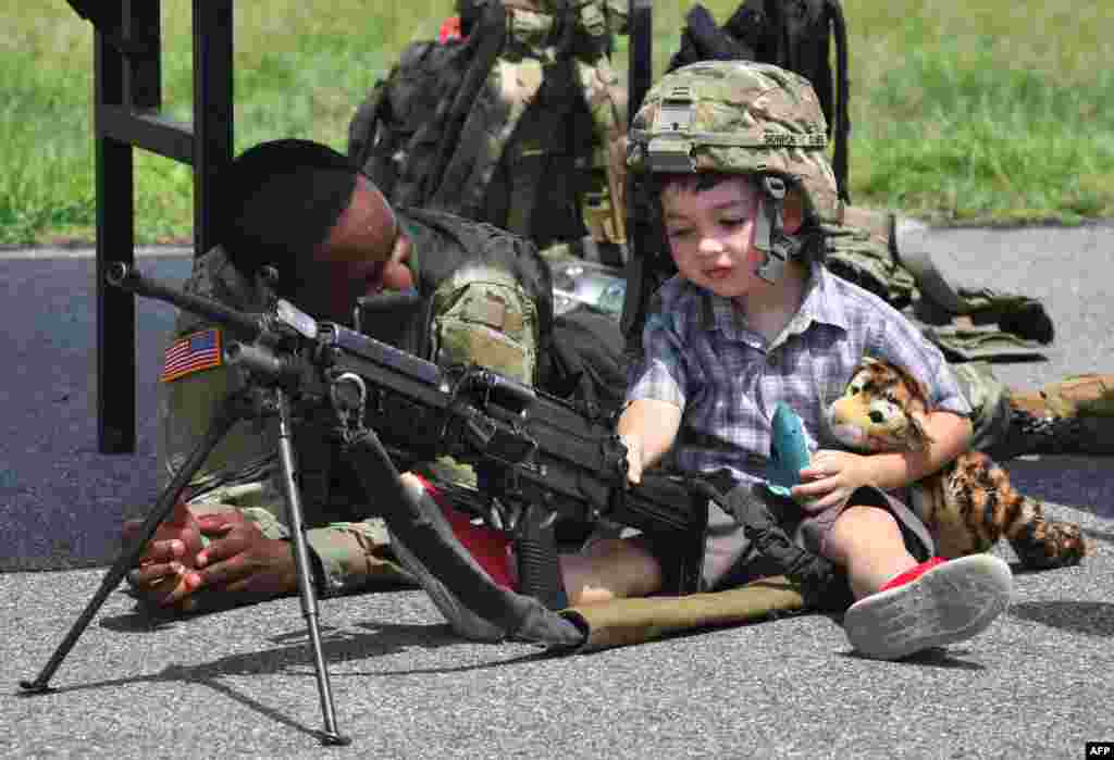 A U.S. soldier looks at a boy posing with a M249 light machine gun during a ceremony to commemorate the 75th anniversary of the Eighth US Army at Camp Humphreys in Pyeongtaek, South Korea, June 8, 2019.