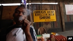 FILE - An unidentified man smokes marijuana at the New Afrika Shrine next to a no drugs sign in Lagos, Nigeria.