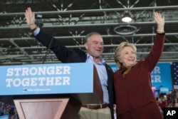 Democratic presidential nominee Hillary Clinton and her running mate, Virginia Sen. Tim Kaine, wave at supporters during a campaign event at Taylor Allderdice High School in Pittsburgh, Pa., Oct. 22, 2016.