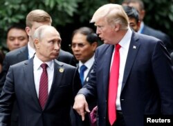 U.S. President Donald Trump and Russia's President Vladimir Putin talk during the photo session at the APEC Summit in Danang, Vietnam, Nov. 11, 2017.