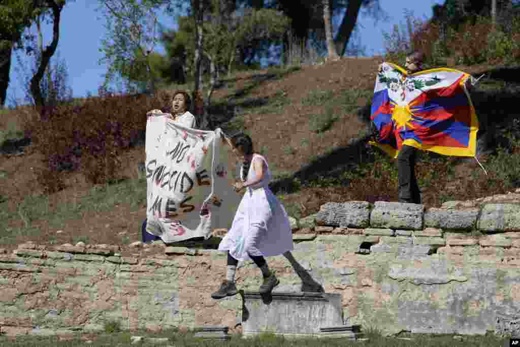 Protesters displaying a Tibetan flag and a banner reading &quot;No genocide games&quot; enter the grounds during the lighting of the Olympic flame at Ancient Olympia site, birthplace of the ancient Olympics in southwestern Greece.