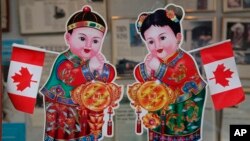 2010年2月18日，加拿大的不列颠哥伦比亚省的温哥华，在中国城一座商业大楼的入口处，有加拿大国旗和华人庆祝农历新年的招财进宝童男童女画像。