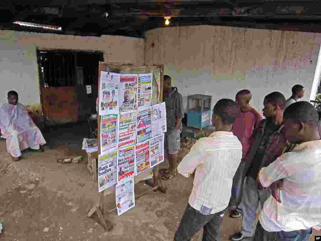 A group of people read the headlines of a newspaper that reads &#39;Burn all bodies&#39; in the city of Monrovia, Liberia, July 31, 2014.