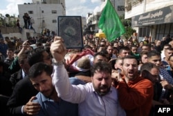 FILE - A mourner holds the Koran, Islam's holy book, in front of Palestinians carrying the body of one of five Palestinians killed by Israeli security forces following attempted stabbing attacks, during a funeral procession in Hebron, West Bank, Oct. 31, 2015.