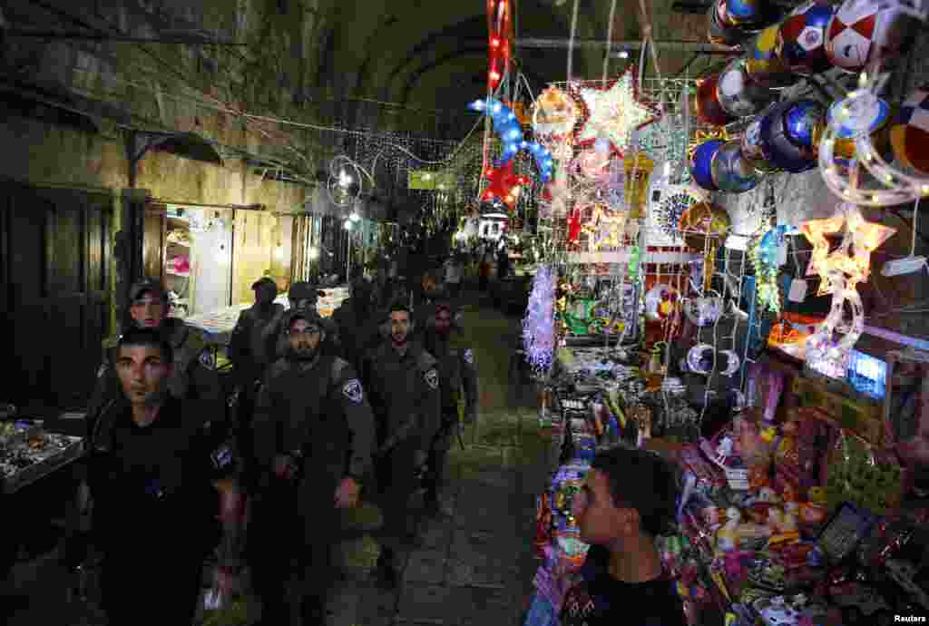Israeli security forces pass by a shop selling decorations as they patrol an alley in Jerusalem&#39;s Old City, July 8, 2013. 