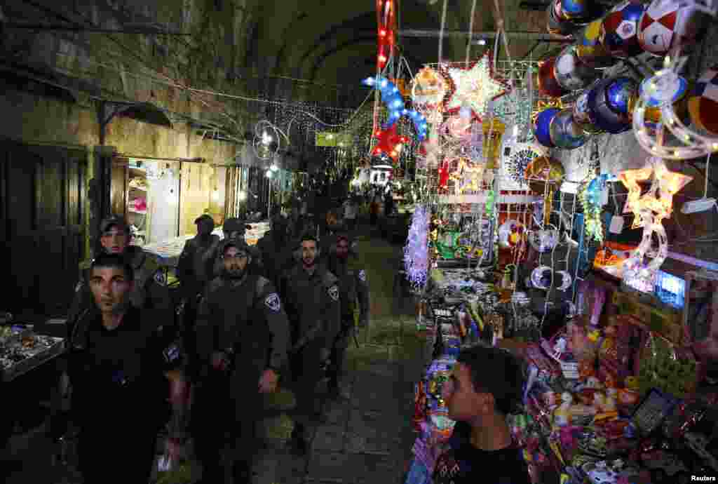 Israeli security forces pass by a shop selling decorations as they patrol an alley in Jerusalem's Old City, July 8, 2013.
