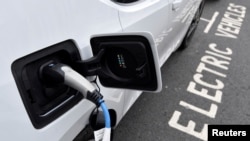 FILE - An electric car is charged at a roadside EV charging point, in London, Britain, Oct. 19, 2021. 