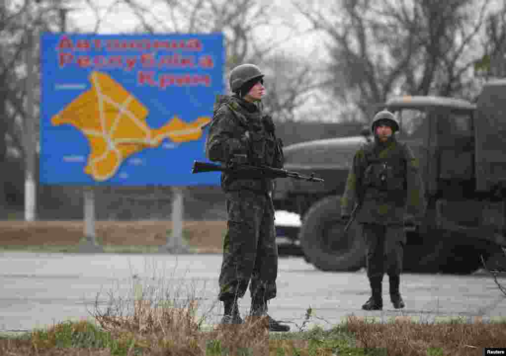 Russian servicemen stand on duty near a map of the Crimea region near the city of Kerch, March 4, 2014.