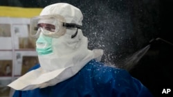Un trabajador de la salud es desinfectado en un entrenamiento para tratar pacientes de ébola.