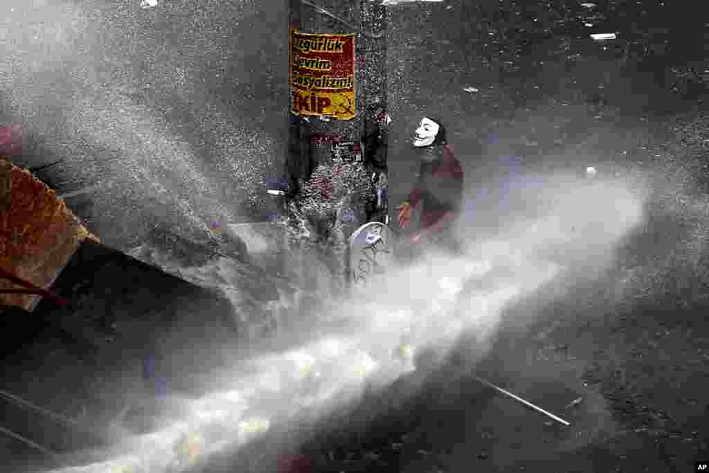 A protester tries take cover from a water cannon fired by police during clashes in Taksim Square in Istanbul, June 11, 2013.
