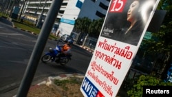 A motorcyclist rides past an election campaign poster of the ruling Pheu Thai Party, featuring a portrait of Prime Minister Yingluck Shinawatra, in central Bangkok on January 3, 2014.