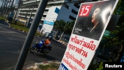 FILE - A motorcyclist rides past an election campaign poster of the ruling Pheu Thai Party, featuring a portrait of Prime Minister Yingluck Shinawatra, in central Bangkok, Jan. 3, 2014.